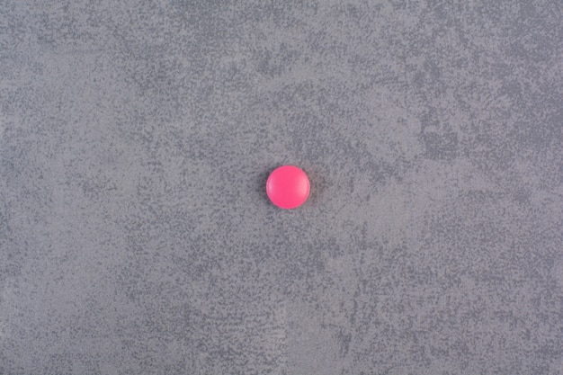 Singola pillola rosa sul tavolo di marmo.