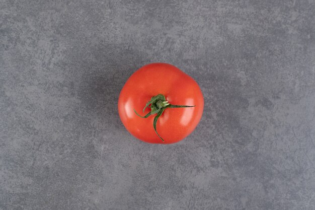Singolo pomodoro rosso su sfondo marmo. Foto di alta qualità