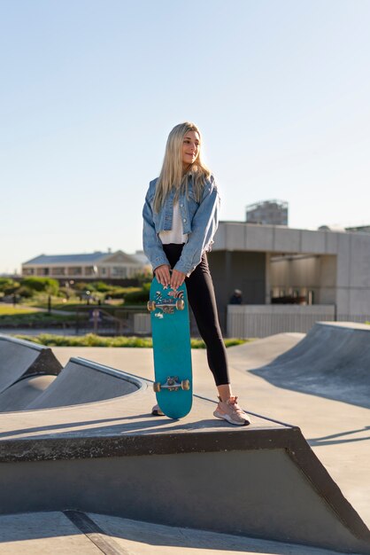 Skateboard della holding della ragazza di smiley di vista frontale