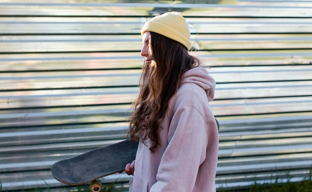 Skateboard teenager della holding della ragazza del colpo medio