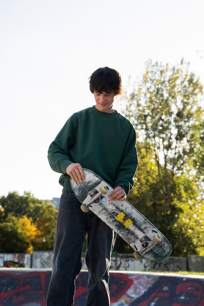 Skateboard teenager della tenuta di vista frontale