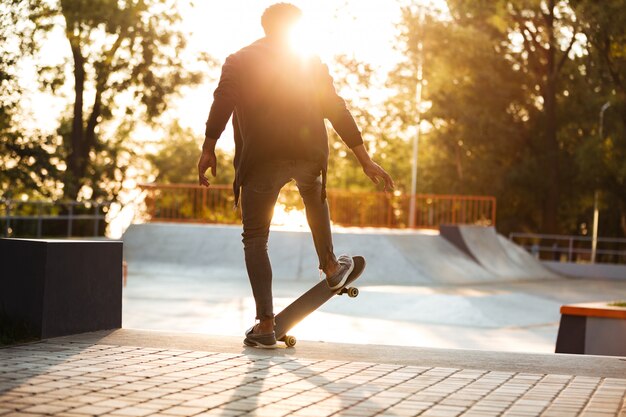 Skateboarder africano che pattina su una rampa concreta di skateboard