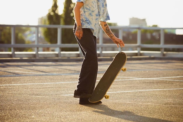 Skateboarder che fa un trucco per le strade della città, sole