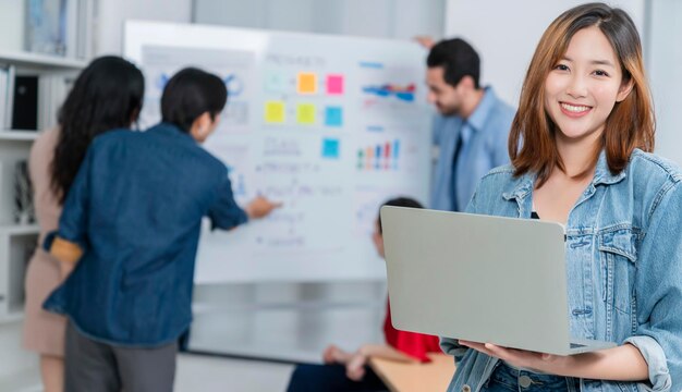 Smart Asian startup piccolo imprenditore in piedi ritratto fiducioso con amici partner incontro casuale brainstorming con lavagna bianca e analisi del grafico cartaceo finanziario aziendale in background dell'ufficio