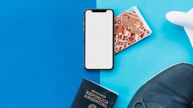 Smart phone con display bianco; carta geografica; passaporto; aeroplano giocattolo e scarpe su sfondo chiaro e scuro