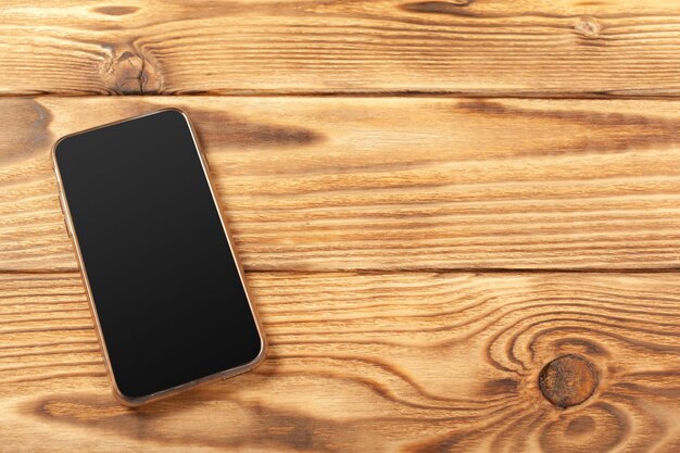 Smartphone con schermo vuoto su sfondo di legno
