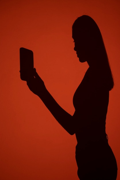 Smartphone della tenuta dell'ombra della donna di vista laterale