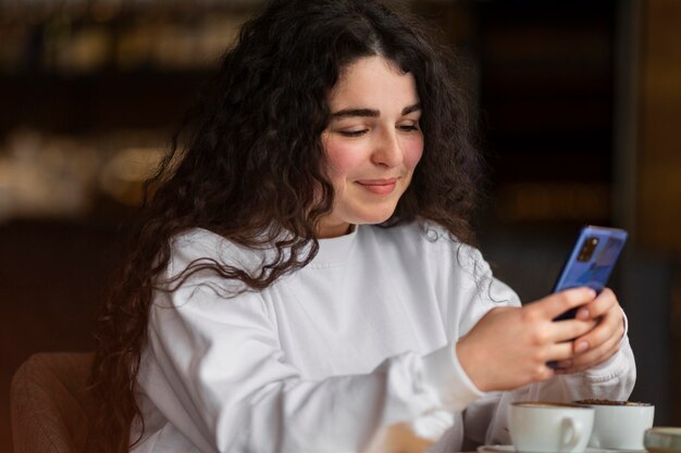 Smartphone della tenuta della donna del colpo medio