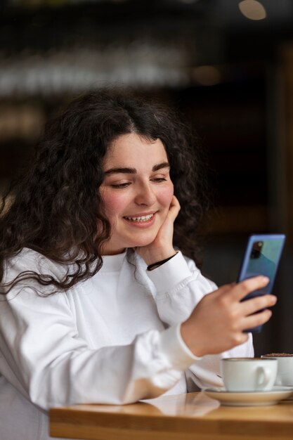 Smartphone della tenuta della donna del colpo medio