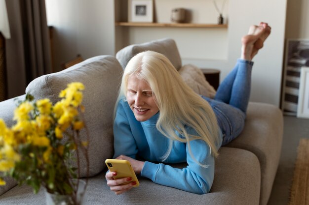 Smartphone della tenuta della donna dell'albino del colpo pieno