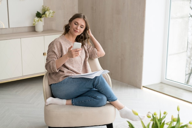 Smartphone della tenuta della donna della foto a figura intera