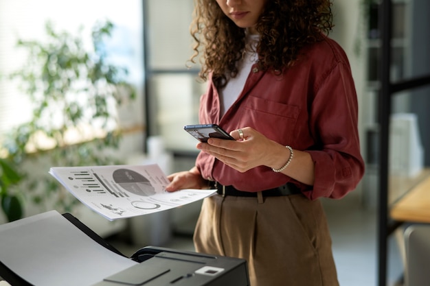 Smartphone della tenuta della donna di vista laterale