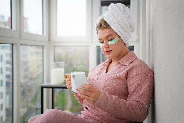 Smartphone della tenuta della donna di vista laterale