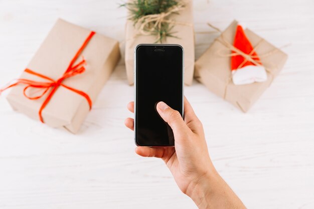 Smartphone della tenuta della persona davanti alle scatole di regalo