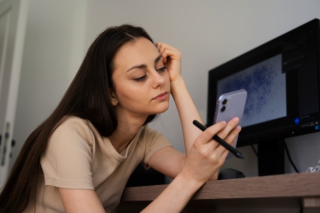 Smartphone della tenuta della ragazza di vista laterale