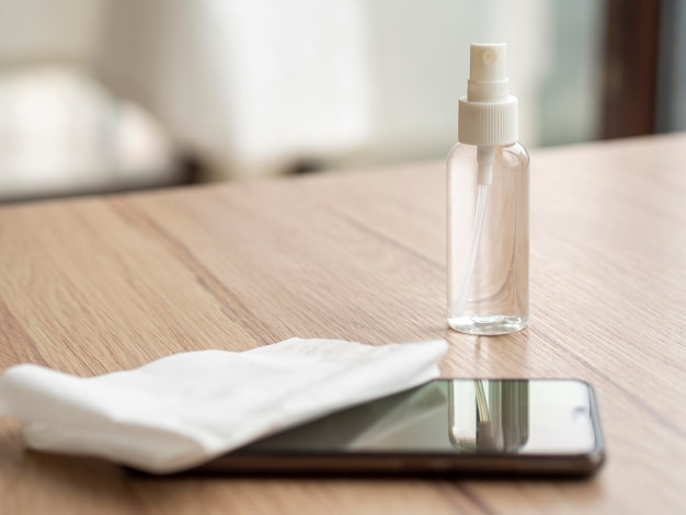 Smartphone e soluzione detergente sulla scrivania con tovagliolo