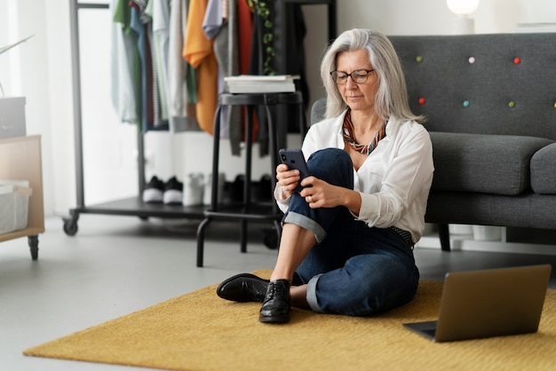 Smartphone senior della tenuta della donna del colpo pieno