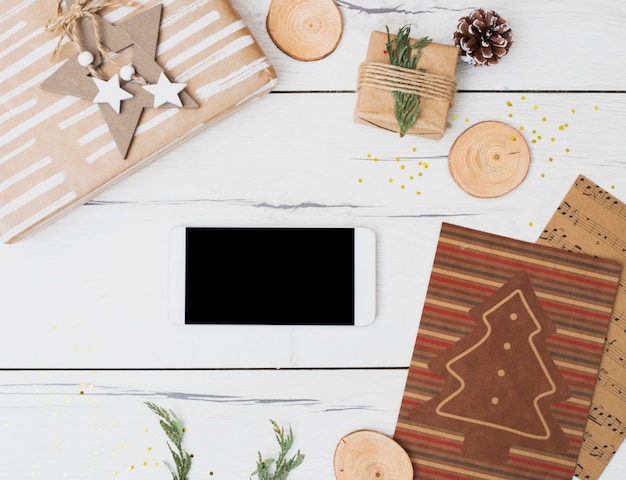 Smartphone tra scatole regalo in involucri e decorazioni natalizie