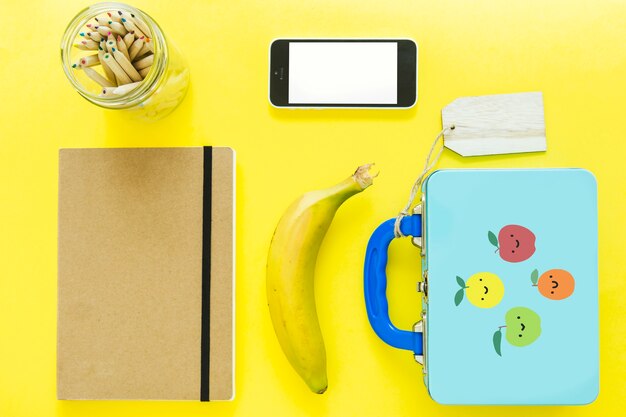 Smartphone vicino a lunchbox e articoli di cancelleria