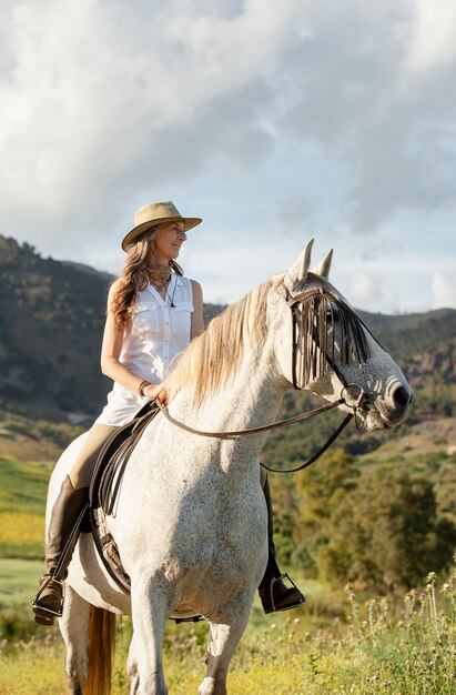 Smiley agricoltore femminile passeggiate a cavallo nella natura