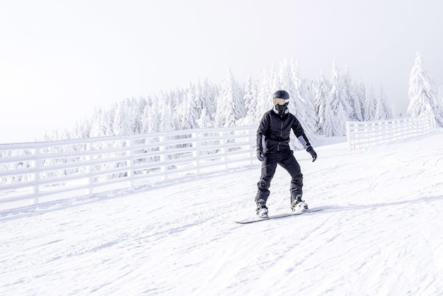 Snowboarder in movimento a cavallo giù per la collina nella località di montagna