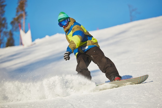 Snowboarder scorrevole dalla montagna in giornata invernale