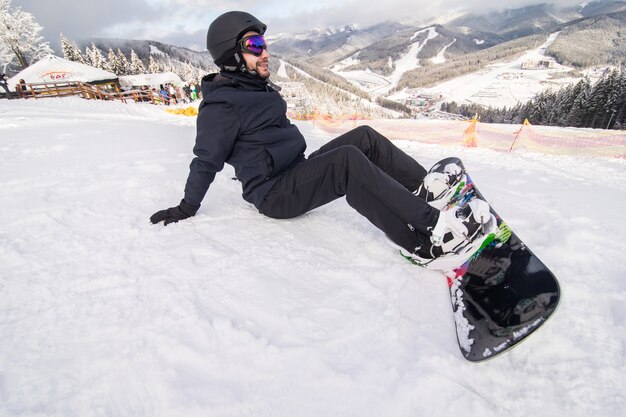 Snowboarder sui bottoni della collina che si fissano prima della corsa sulla collina della neve