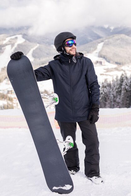 Snowboarder tenere lo snowboard in cima alla collina vicino ritratto, montagne di neve snowboard sui pendii.