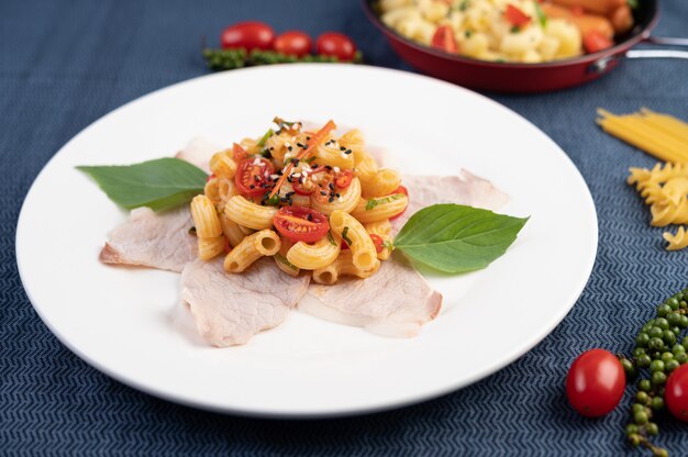 Soffriggere i maccheroni sulla carne di maiale superiore all'incirca in un piatto bianco.