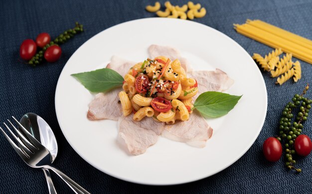 Soffriggere i maccheroni sulla carne di maiale superiore all'incirca in un piatto bianco.