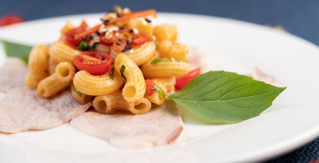 Soffriggere i maccheroni sulla carne di maiale superiore all'incirca in un piatto bianco.