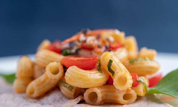 Soffriggere i maccheroni sulla carne di maiale superiore all'incirca in un piatto bianco.