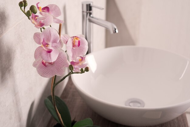 Soft focus di orchidee fioriscono accanto a un lavandino in un bagno