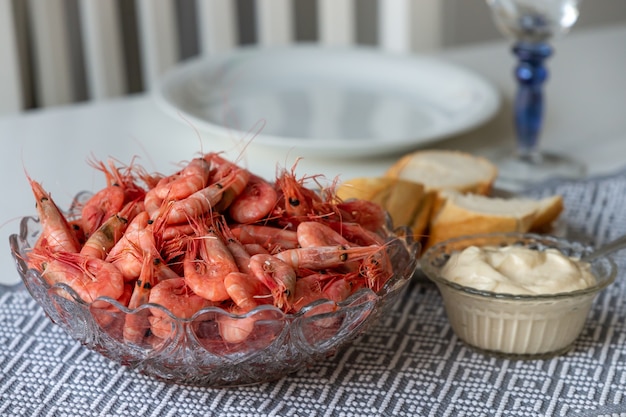 Soft focus gamberetti cotti in una ciotola di vetro con salsa all'aglio e pane su un tavolo da cucina