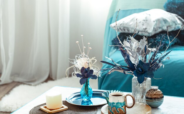 Soggiorno moderno, con fiori artificiali in un vaso e oggetti di arredamento per la casa sul tavolo luminoso in legno.