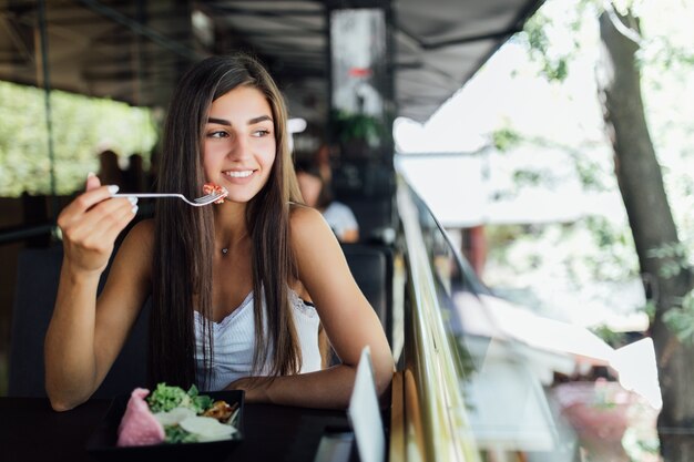 Sognando la donna che mangia cibo sano seduto nel bellissimo interno