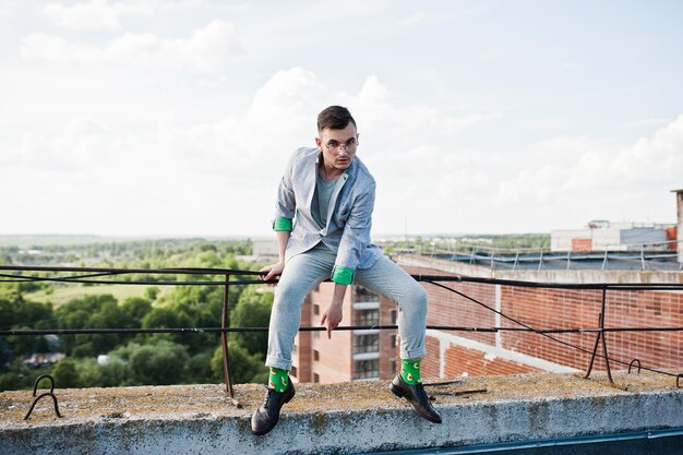 Sognatore elegante uomo macho in abito grigio e occhiali posato sul tetto