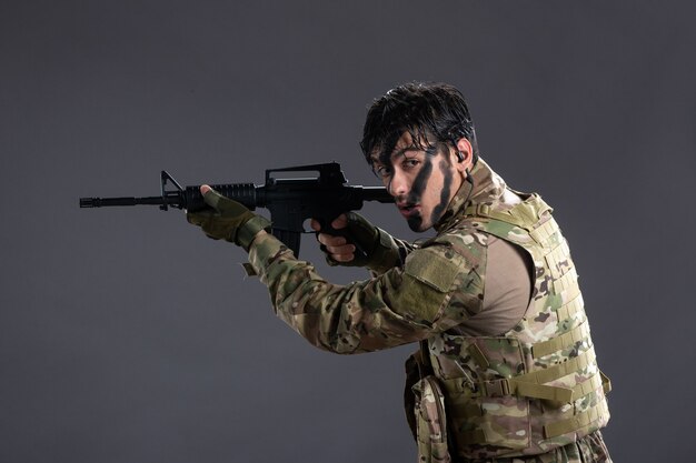 Soldato coraggioso di vista frontale che combatte in camuffamento con la parete scura della mitragliatrice