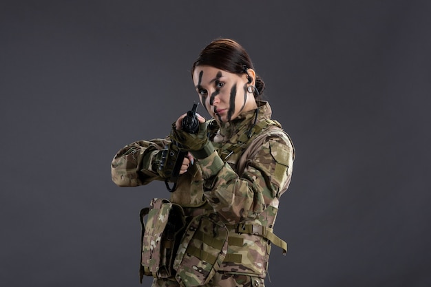 Soldato femminile di vista frontale in camuffamento con la mitragliatrice sulla guerra del carro armato della scrivania scura israele