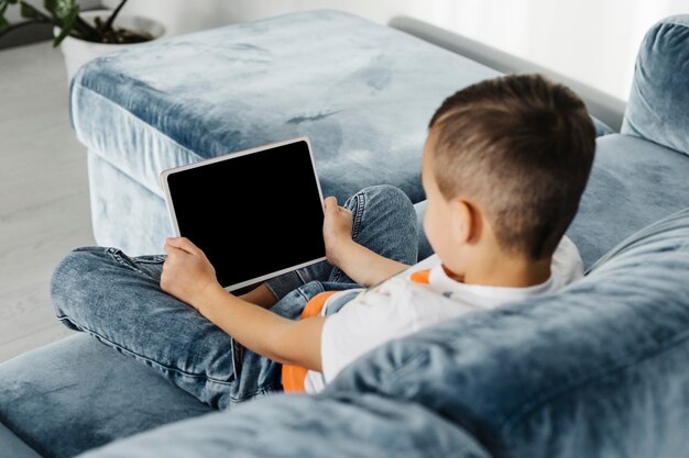 Sopra la spalla vista ragazzo utilizzando una tavoletta digitale