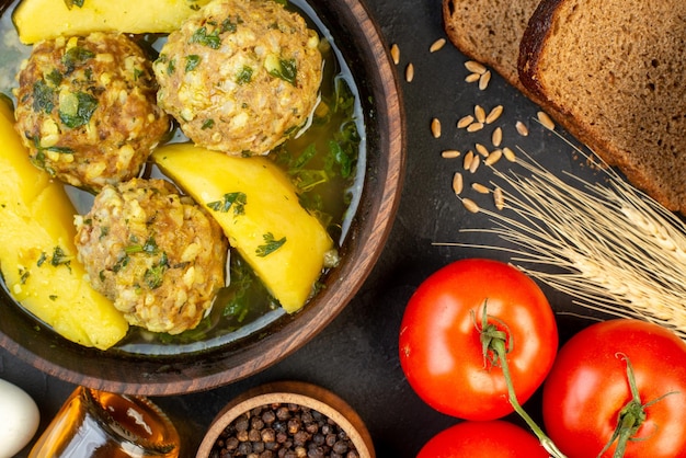 Sopra la vista del delizioso pasto di polpette di verdure fresche olio caduto bottiglia fette di pane su sfondo nero