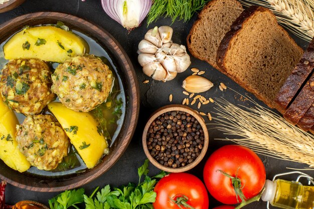 Sopra la vista del gustoso pasto di polpette di verdure fresche picchi di fette di pane bottiglia di olio caduta verde su sfondo nero