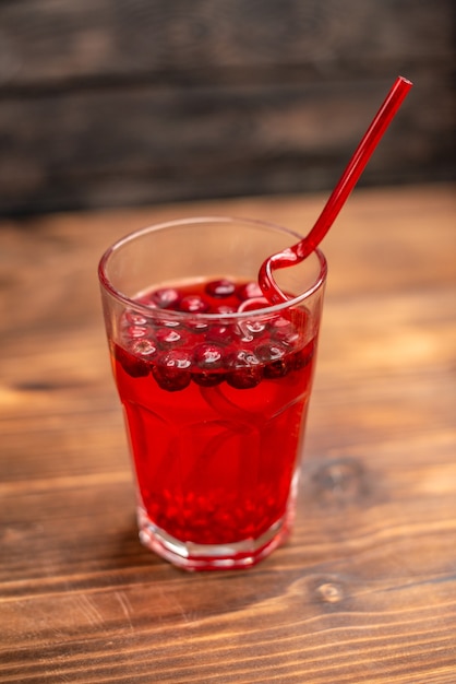 Sopra la vista del succo di ribes fresco biologico naturale in un bicchiere servito con un tubo su un tavolo di legno