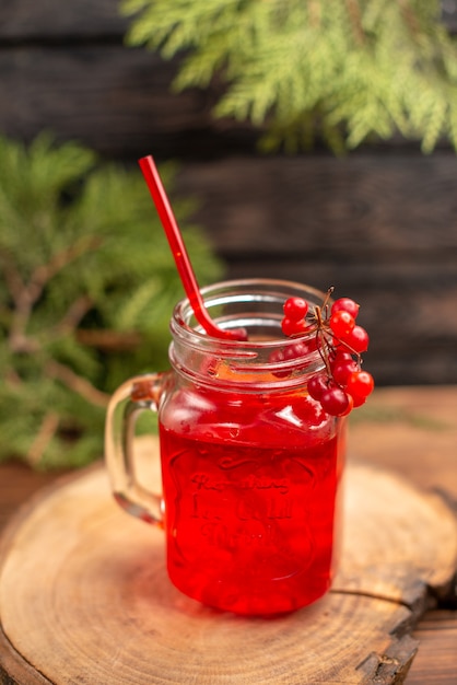 Sopra la vista del succo di ribes fresco in un bicchiere servito con un tubo su un tagliere di legno