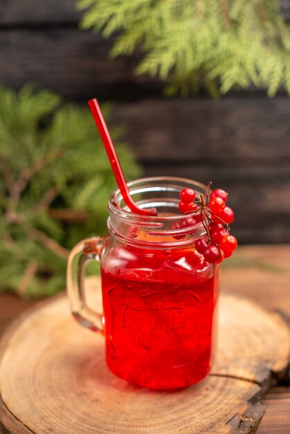 Sopra la vista del succo di ribes fresco in un bicchiere servito con un tubo su un tagliere di legno