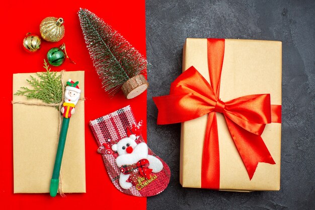 Sopra la vista dell'atmosfera natalizia con il calzino del regalo degli accessori della decorazione dell'albero di Natale su backgroud rosso e nero