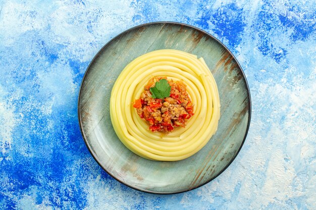 Sopra la vista della cena con deliziosi spaghetti su un piatto grigio su sfondo blu