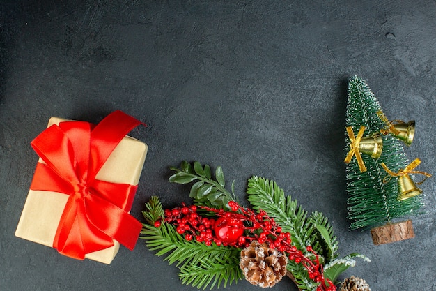 Sopra la vista della confezione regalo con fiocco rosso a forma di fiocco rami di abete cono albero di Natale cono su sfondo nero