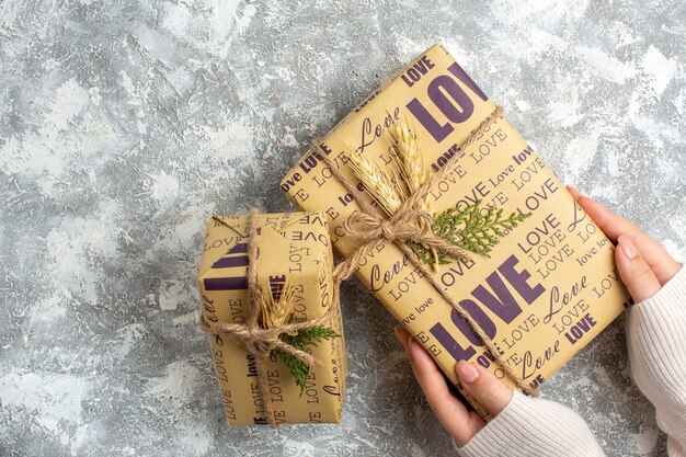 Sopra la vista della mano che tiene un bellissimo regalo confezionato per Natale sulla superficie del ghiaccio
