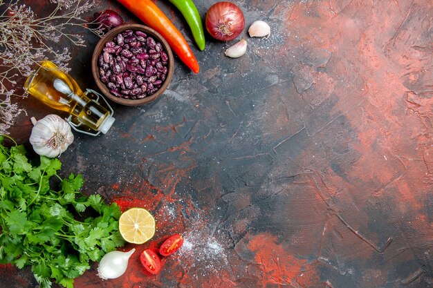 Sopra la vista della preparazione della cena con cibi e fagioli caduti bottiglia di olio e un mazzo di limone verde pomodoro sul tavolo di colori misti